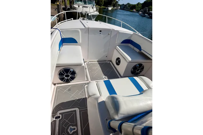 Slide: The Image of 2001 Intrepid 322 Cuddy boat interior with blue and white seating, docked by a canal. - 6