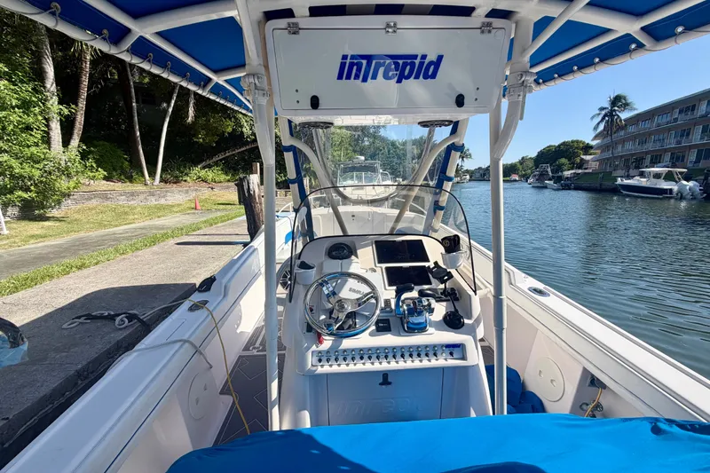 Slide: The Image of 2001 Intrepid 322 Cuddy boat interior with steering wheel and controls, docked by a canal. - 4
