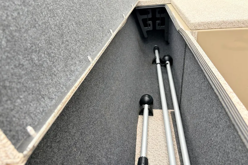 Slide: The Image of 2021 G3 Sportsman 1610 boat storage compartment with carpeted interior and rod holders. - 16