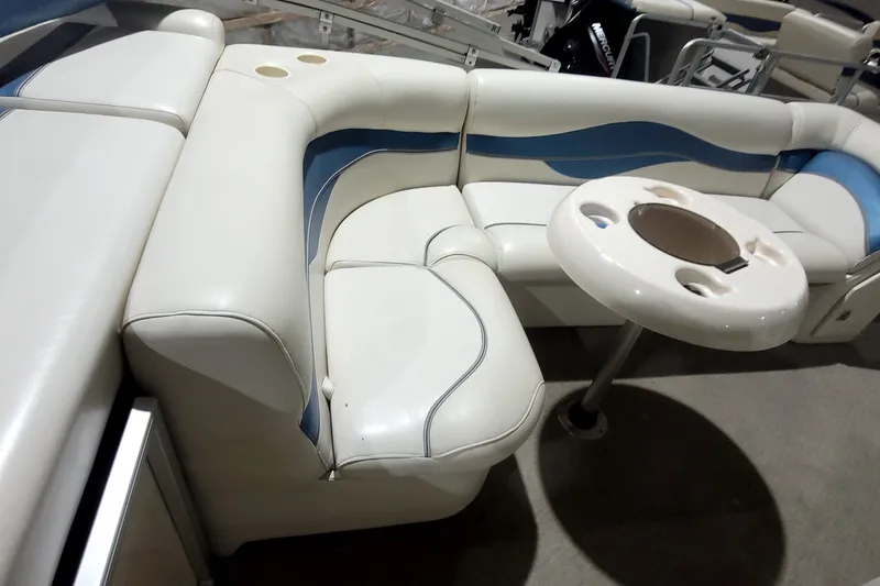 Slide: The Image of 2006 Sweetwater 2386RE boat interior with white and blue seating and a round table. - 18