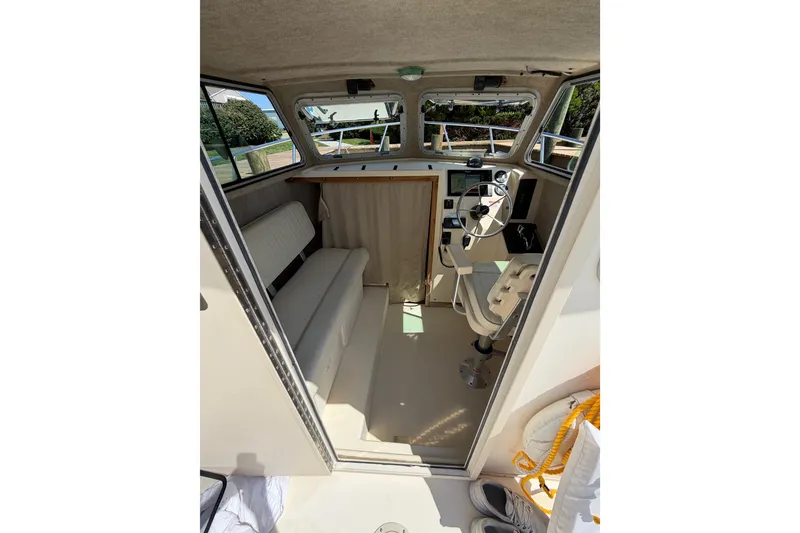 Slide: The Image of Interior of a 2005 Parker 2520 Modified Vee Sport Cabin boat, featuring helm and seating. - 19