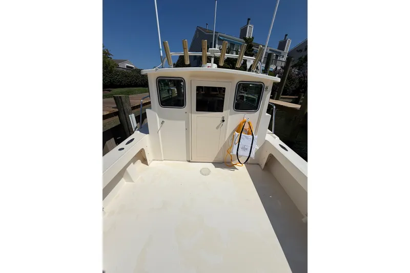 Slide: The Image of 2005 Parker 2520 Modified Vee Sport Cabin boat docked, showcasing spacious deck and cabin. - 17
