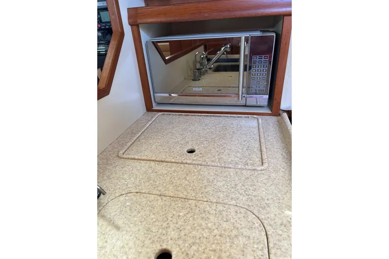 Slide: The Image of 2006 Island Packet 440 yacht kitchen with microwave and beige countertop. - 58