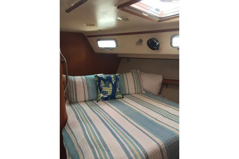 Slide: The Image of Cozy cabin interior of 2006 Island Packet 440 sailboat with striped bedding and decorative pillow. - 57