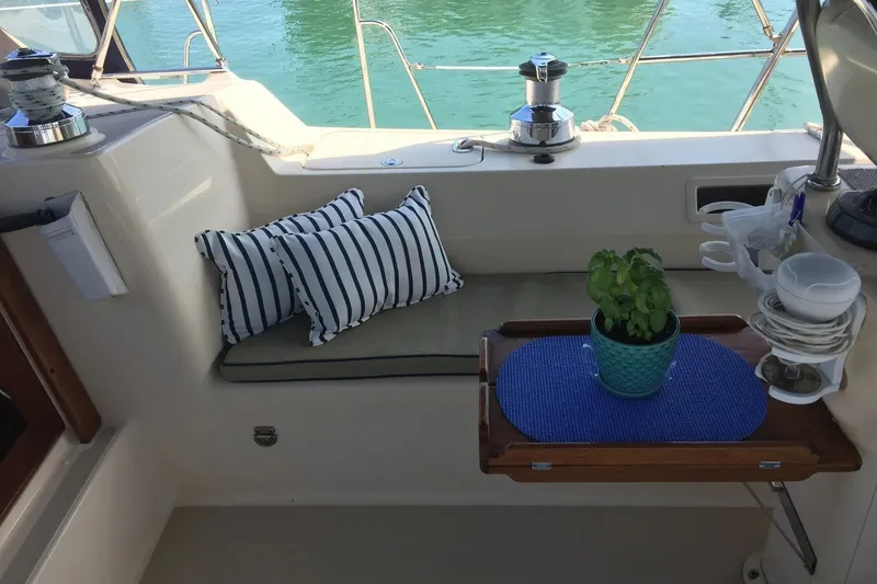 Slide: The Image of Cozy seating area on 2006 Island Packet 440 sailboat with striped cushions and potted plant. - 16