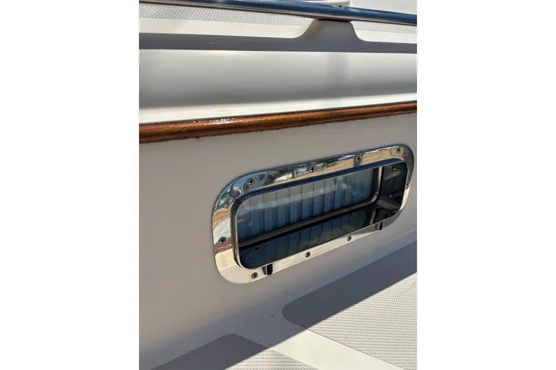 Slide: The Image of Close-up of a 2006 Island Packet 440 boat's polished metal porthole and wooden trim. - 43