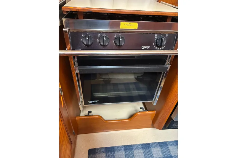 Slide: The Image of 2006 Island Packet 440 yacht kitchen oven with control knobs and wooden cabinetry. - 61