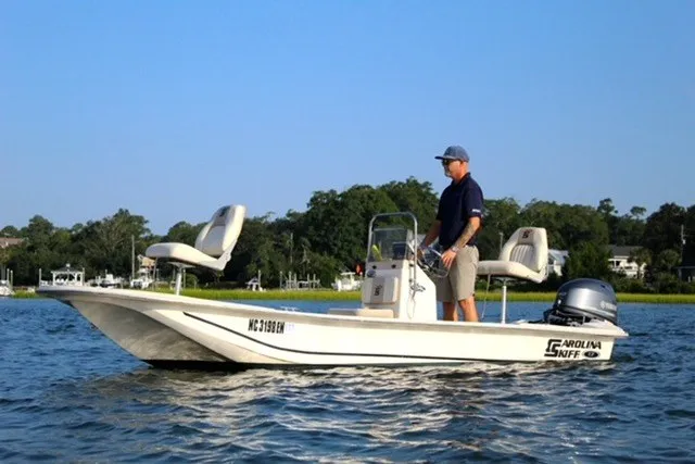 Slide: The Image of 2019 Carolina Skiff 17 JV CC boat on water with person steering. - 2