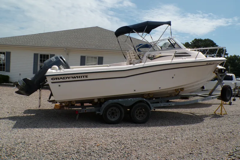The Image of 2005 Grady-White Seafarer 226 boat on trailer, parked on gravel near a house. - 0