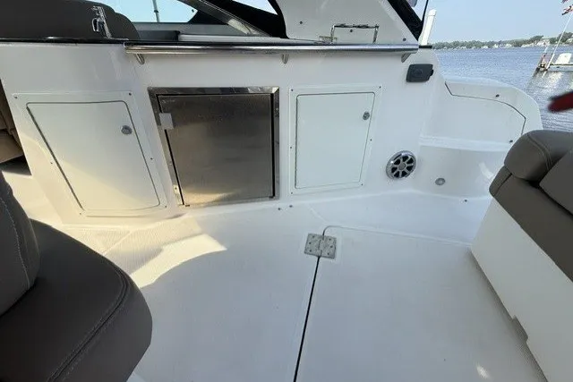 Slide: The Image of 2015 Regal 32 Express boat interior with storage compartments and seating, docked by the water. - 30