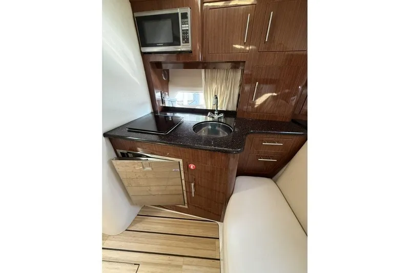 Slide: The Image of 2015 Regal 32 Express yacht kitchen with microwave, sink, and wooden cabinetry. - 42