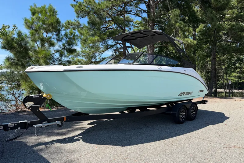 The Image of 2024 Yamaha AR250 boat on trailer, parked outdoors with trees in background. - 0