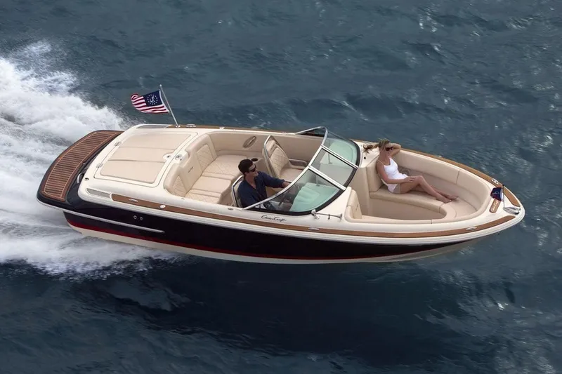 Slide: The Image of A sleek 2019 Chris-Craft Launch 23 boat speeds across the water. Two people relax onboard. - 19