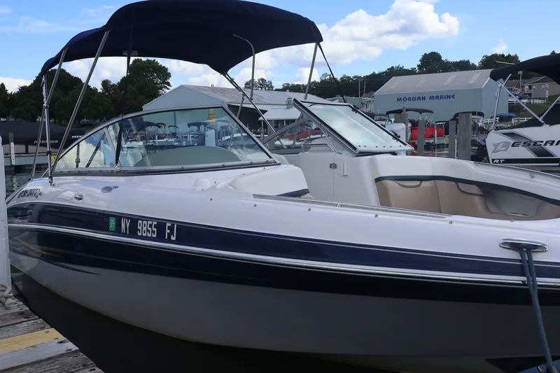 The Image of 2006 Four Winns H240 boat docked at marina with blue canopy. - 0