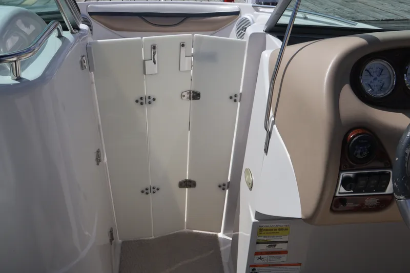 Slide: The Image of Interior view of a 2006 Four Winns H240 boat, featuring a closed cabin door and dashboard controls. - 39