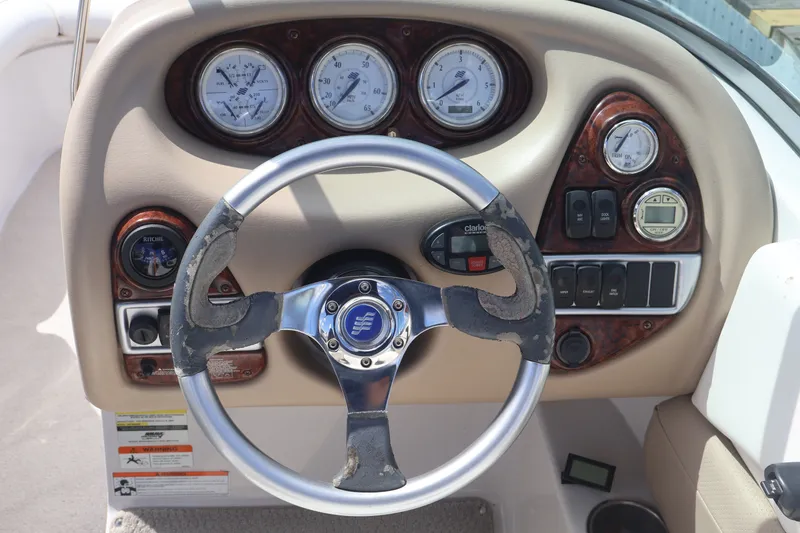 Slide: The Image of Steering wheel and dashboard of 2006 Four Winns H240 boat, featuring gauges and controls. - 34