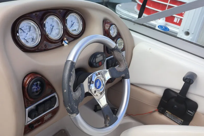 Slide: The Image of 2006 Four Winns H240 boat dashboard with steering wheel and gauges. - 35