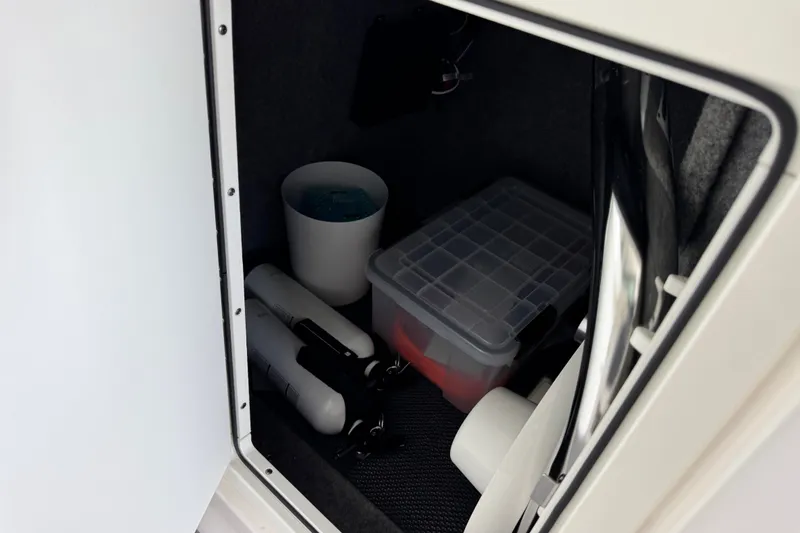 Slide: The Image of Storage compartment in 2019 Chaparral 264 Sunesta boat with various items inside. - 19