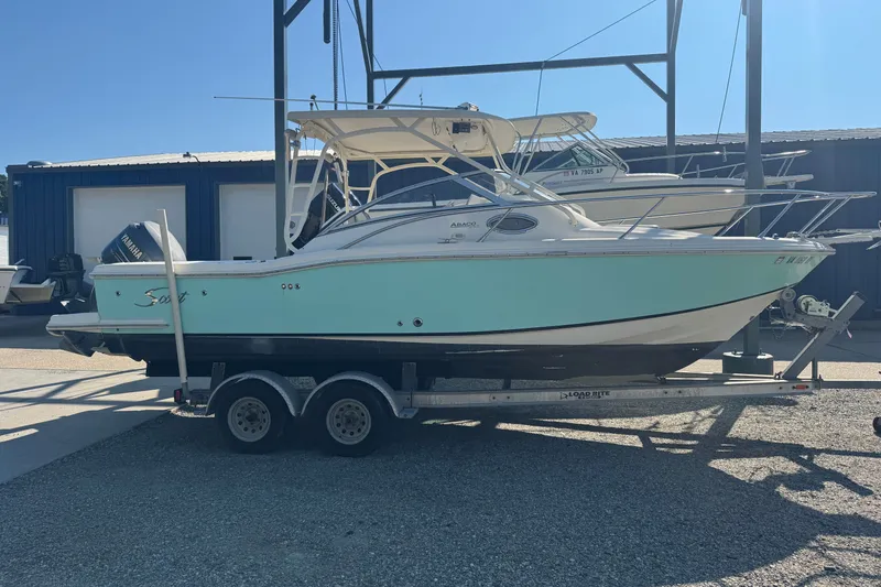 The Image of 2004 Scout 242 Abaco boat on trailer, light blue hull, parked outdoors. - 1