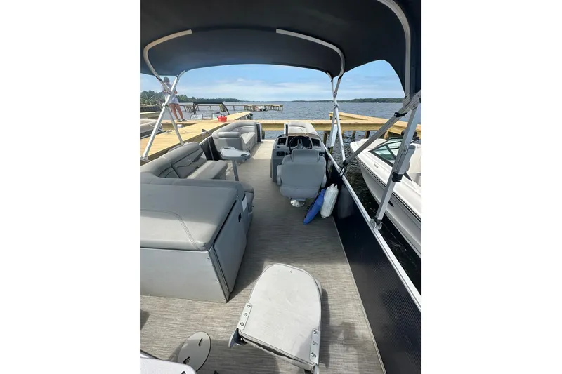 Slide: The Image of 2022 Bennington 22 SS pontoon boat interior with seating, docked by a lake. - 6