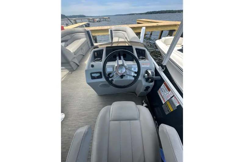 Slide: The Image of 2022 Bennington 22 SS boat interior with steering wheel and seating, docked by the water. - 7