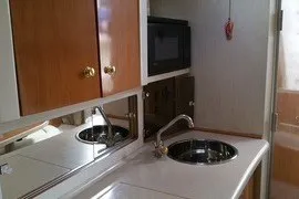 Slide: The Image of 2001 Regal Commodore 2760 boat kitchen with sink, microwave, and wooden cabinets. - 15