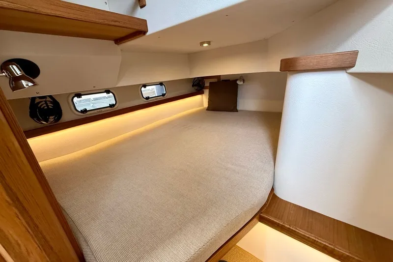 Slide: The Image of 2027 Targa 32 cabin interior with cozy bed, ambient lighting, and wooden accents. - 18