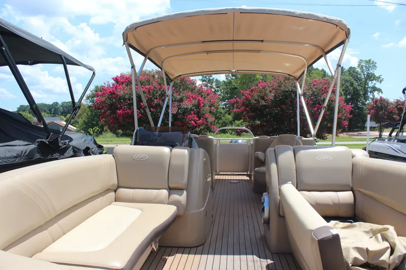 Slide: The Image of 2018 Harris Solstice 240 pontoon boat with beige seating and canopy, surrounded by trees. - 3