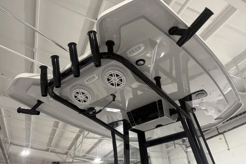 Slide: The Image of Tidewater 2300 Carolina Bay 2026 boat T-top with rod holders and speakers in a showroom. - 7