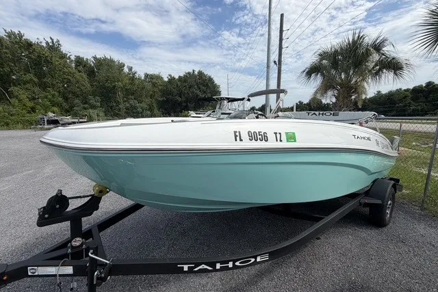 Slide: The Image of 2025 Tahoe T18 boat on trailer, parked outdoors with trees and palm in background. - 5