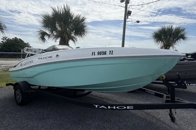 Slide: The Image of 2025 Tahoe T18 boat on trailer, parked outdoors with palm trees in background. - 2