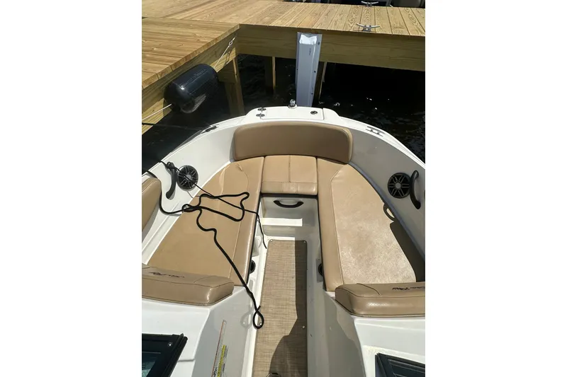 Slide: The Image of 2023 Sea Ray SPX 210 Outboard boat interior with tan seating and dock view. - 9