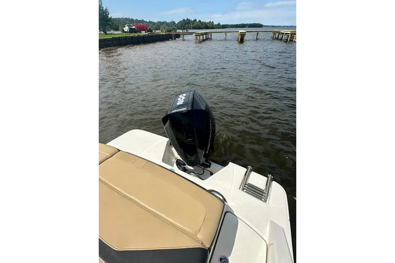 Slide: The Image of 2023 Sea Ray SPX 210 Outboard boat on water near dock, showcasing engine and seating. - 5