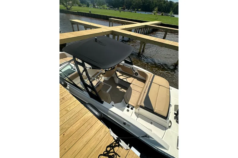 Slide: The Image of 2023 Sea Ray SPX 210 Outboard boat docked, featuring tan seating and black canopy. - 4
