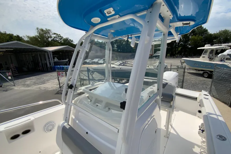 Slide: The Image of 2016 Everglades 230 Center Console boat with blue canopy, docked near storage facility. - 24