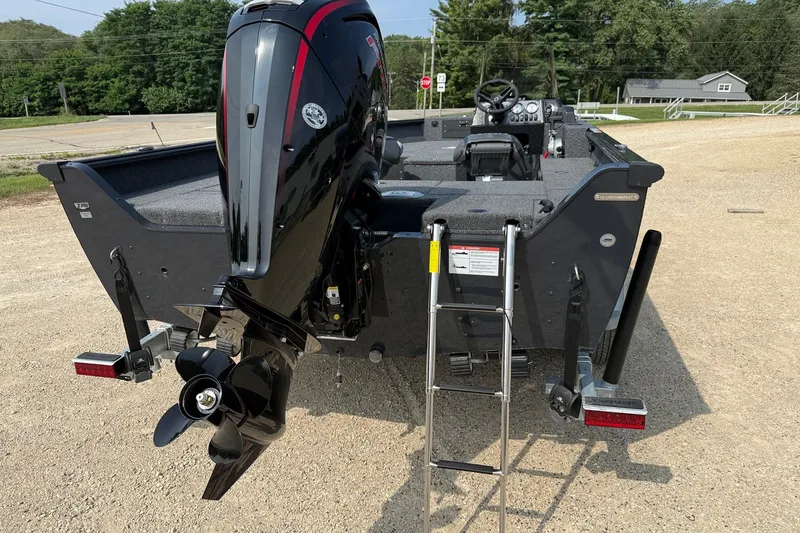 Slide: The Image of 2027 Lund 1800 Adventure SS boat with outboard motor and ladder, parked on gravel. - 3