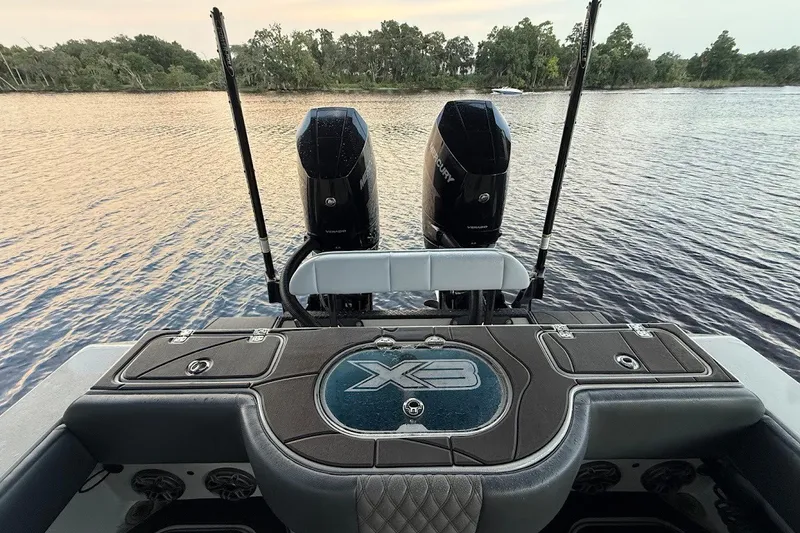 Slide: The Image of 2025 Shallow Sport 32 X3 boat with dual Mercury engines on a serene lake. - 8