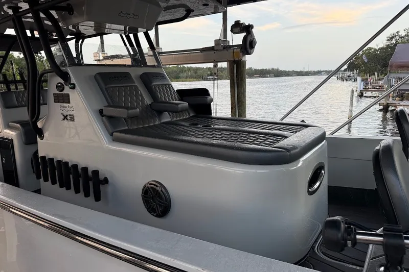 Slide: The Image of 2025 Shallow Sport 32 X3 boat interior with seating and rod holders by the water. - 7