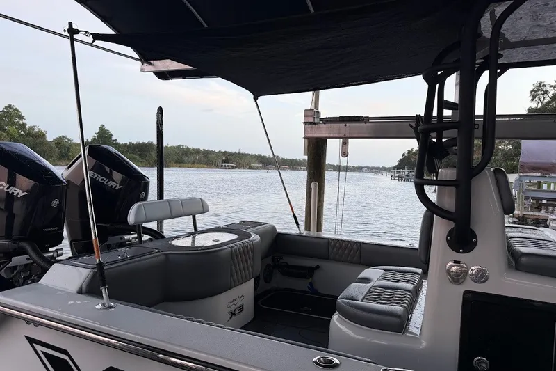 Slide: The Image of 2025 Shallow Sport 32 X3 boat interior with Mercury engines, docked by a scenic waterfront. - 23