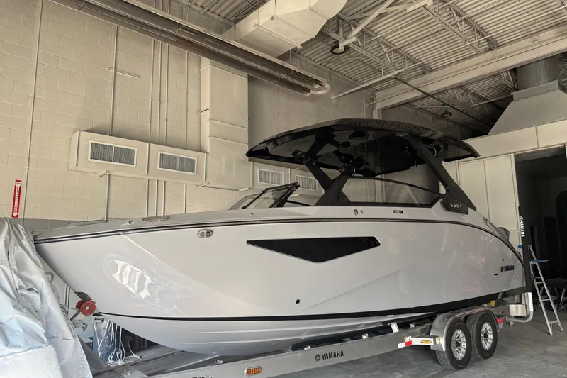 Slide: The Image of 2026 Yamaha Boats 295XD in a garage, sleek design on a trailer. - 0