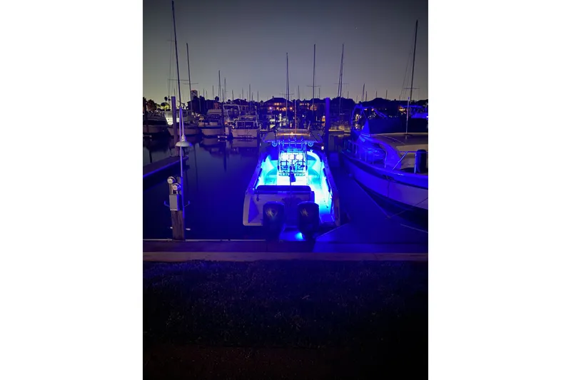 Slide: The Image of 2009 Century 3200 Center Console boat illuminated with blue lights at night in marina. - 58