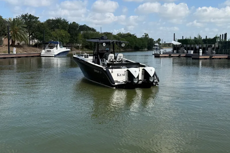 Slide: The Image of 2009 Century 3200 Center Console boat on calm water, surrounded by docks and trees. - 3