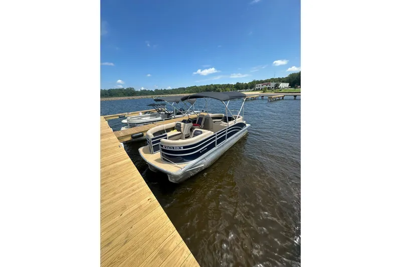 The Image of 2025 Harris Cruiser 210 pontoon boat docked on a sunny lake. - 1