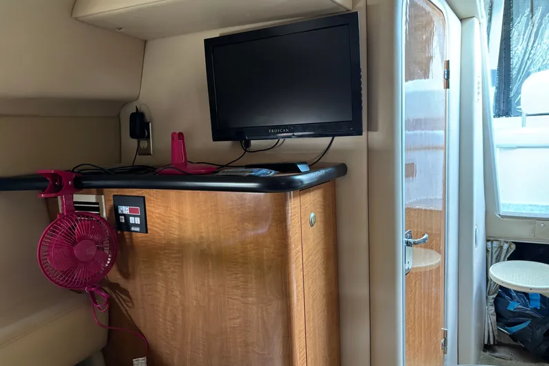 Slide: The Image of Interior of 2003 Maxum 2500 SCR boat with TV, fan, and wooden cabinetry. - 14