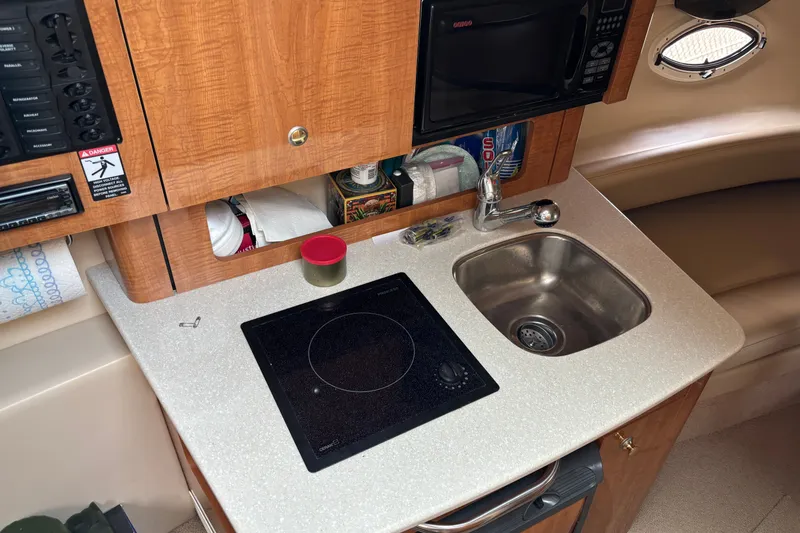 Slide: The Image of 2003 Maxum 2500 SCR boat kitchenette with sink, stove, and microwave. - 10
