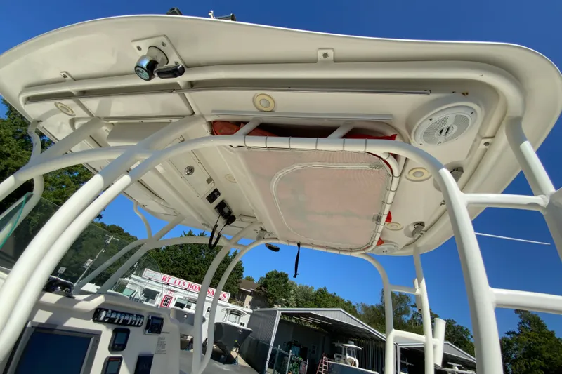 Slide: The Image of 2014 Sailfish 290 CC boat's helm station with T-top and electronics, under clear blue sky. - 21