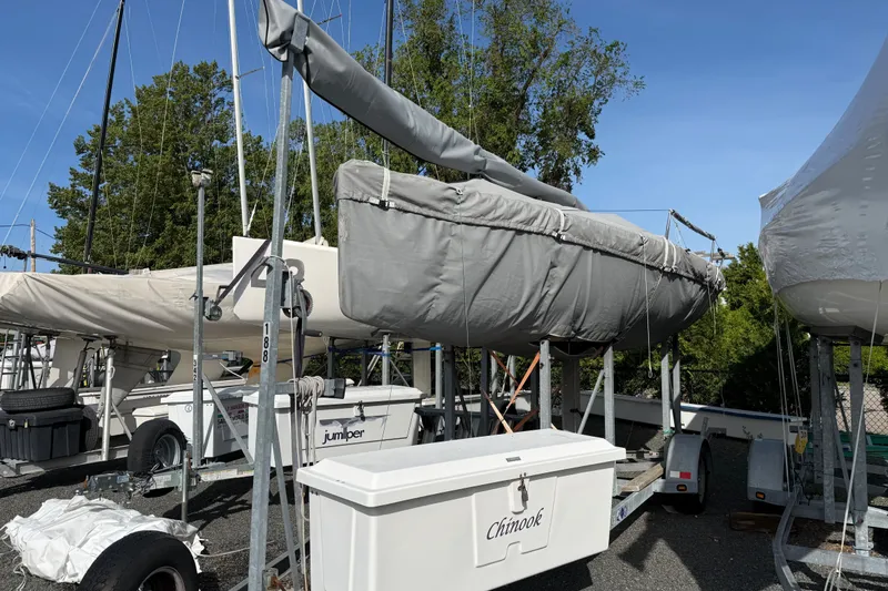 Slide: The Image of Covered 2013 J Boats J/70 sailboat on trailer, surrounded by trees and equipment. - 3