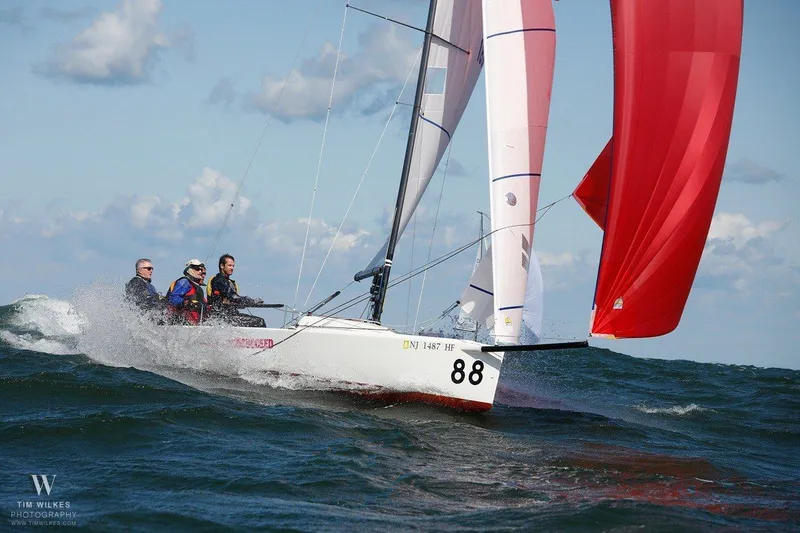 Slide: The Image of A 2013 J/70 sailboat with a red spinnaker sails on rough seas. - 0