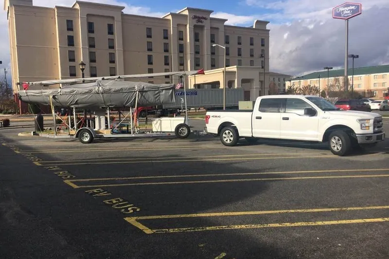 Slide: The Image of White truck towing a covered 2013 J Boats J/70 sailboat in a hotel parking lot. - 4