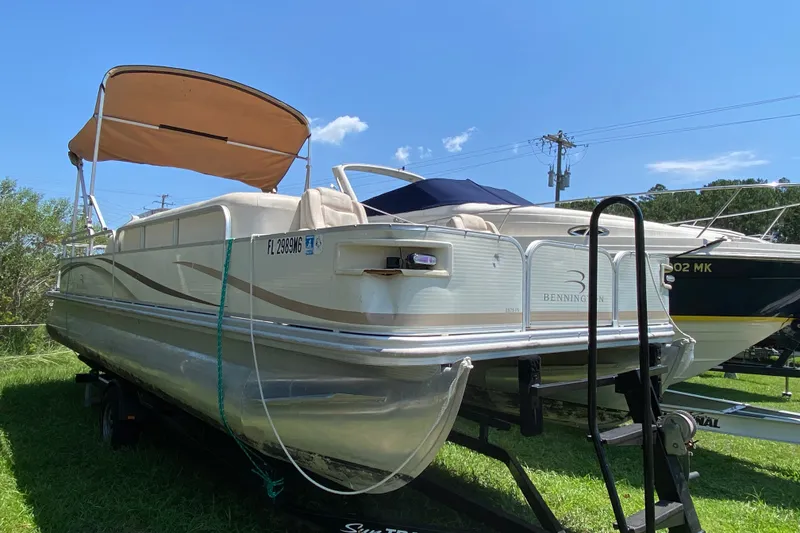 The Image of 2003 Bennington 2575 pontoon boat on trailer, with canopy, parked on grass. - 1